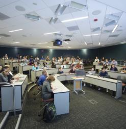 Dozens of people gather in a large lecture hall.