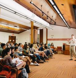 Instructors stand at the front of a lecture hall and speak to Stanford Humanities Institute participants.