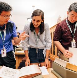 Three students examine rare print materials in Stanford Special Collections.